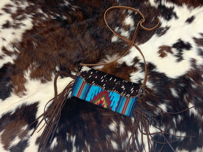 Saddle blanket crossbody purse with hand tooled leather and fringe.